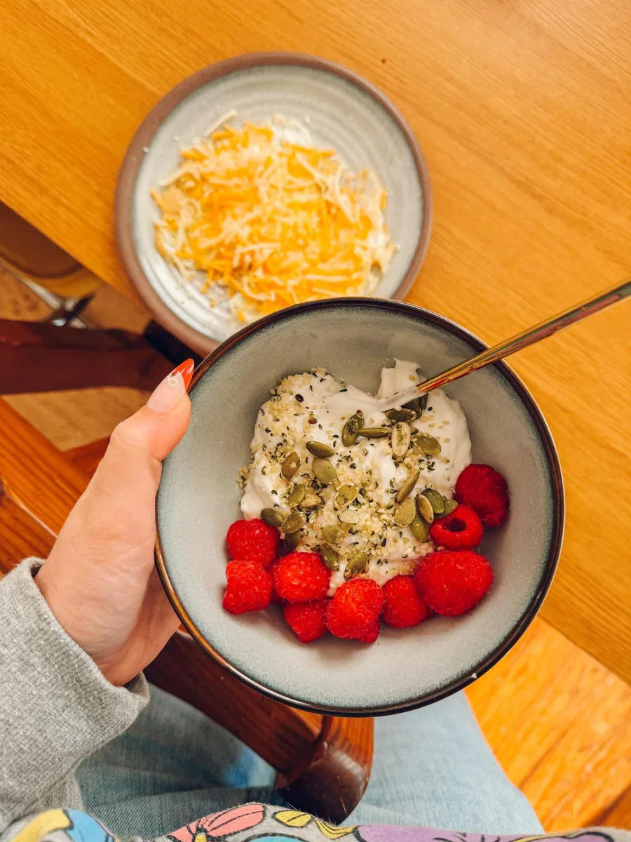 Bowl of yogurt topped with pumpkin seeds and fresh raspberries, a magnesium-rich pregnancy snack.